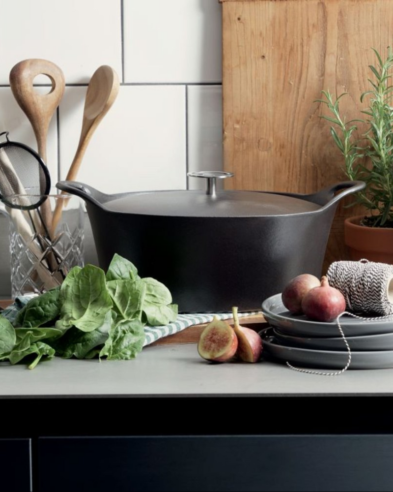 Cocotte ovale Cuisinox 29 cm noire en fonte émaillée, vue de dessus, posée sur un plan de travail.